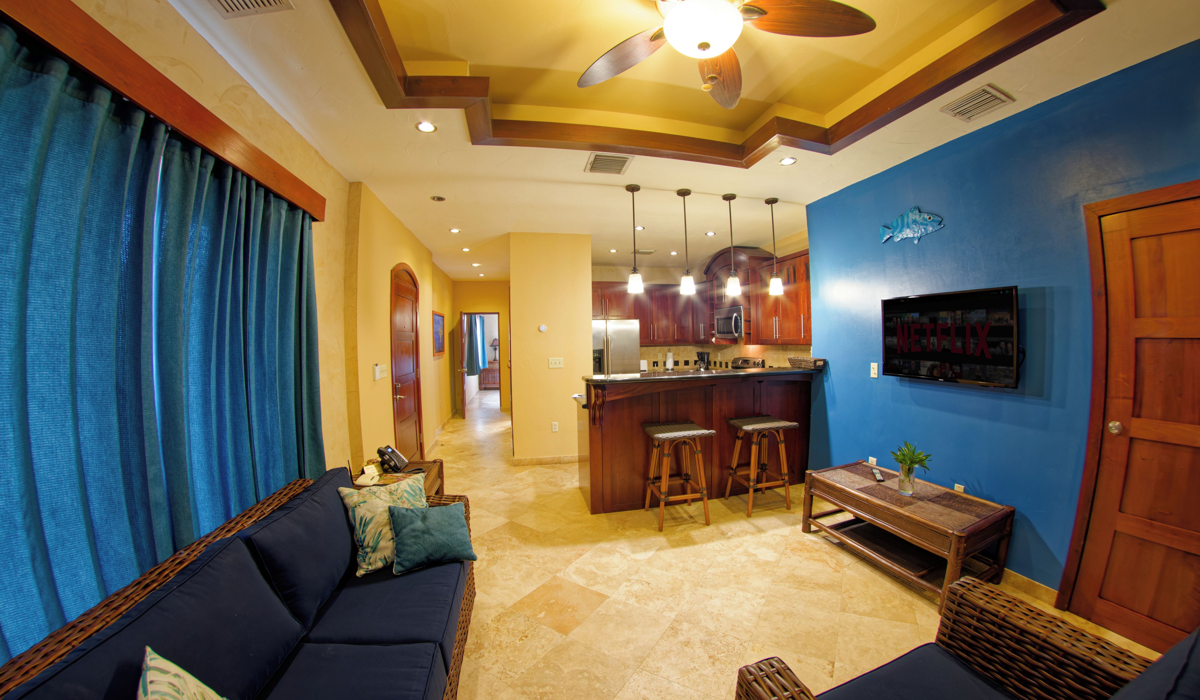 A living room with a sofa, a coffee table, and a TV mounted on the wall.