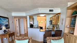 A living room with patterned sofas, a wooden coffee table, and a kitchen area in the background. - Large Oceanfront 2BD/2BA, Sleeps 6, Pool, Kitchen, W/D, Parking, Ormond/Daytona (Ormond Beach)