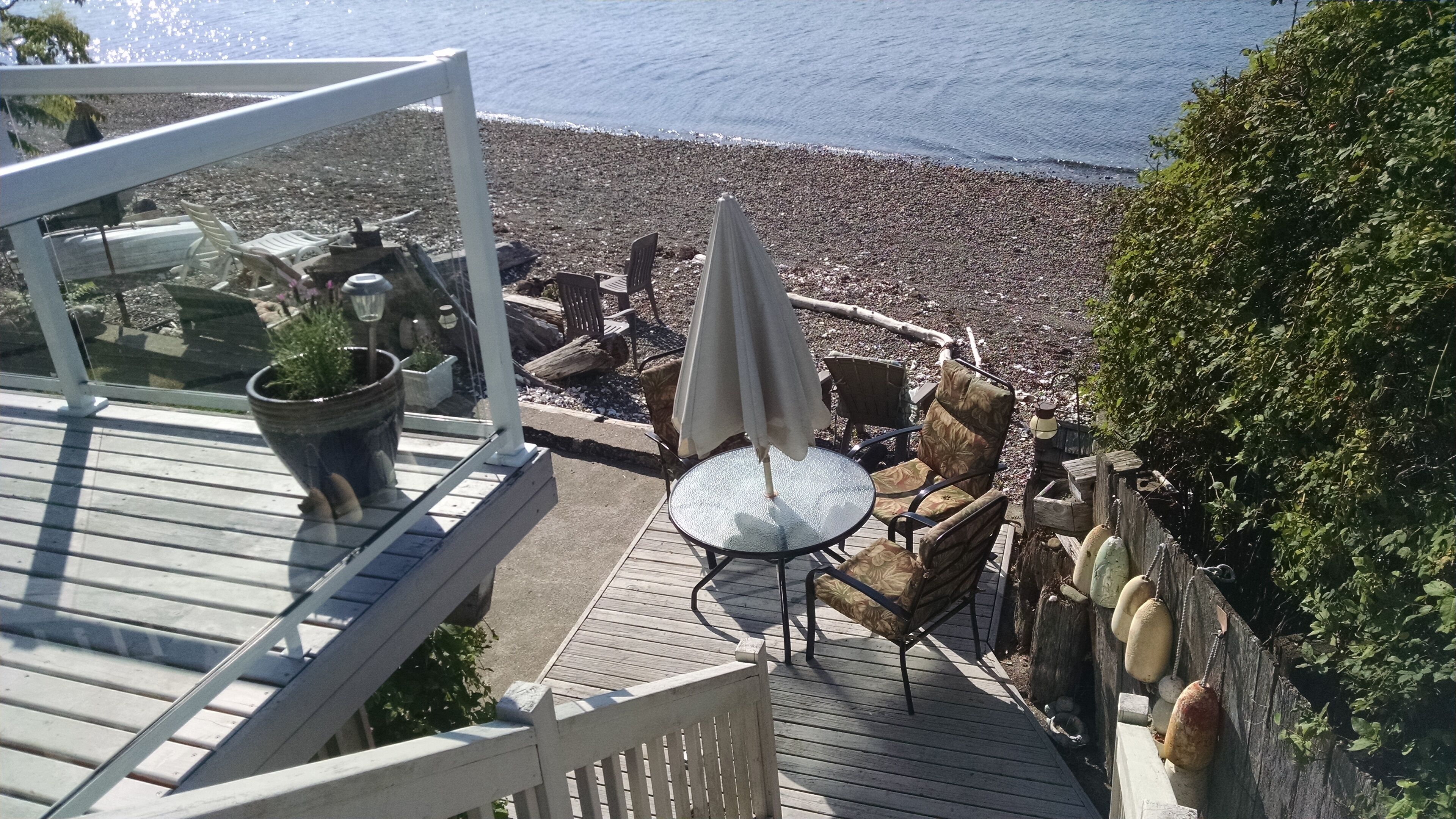 A deck with outdoor seating, overlooking a pebble beach.