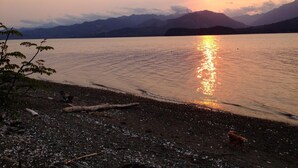 Un atardecer sobre un lago con montañas al fondo.