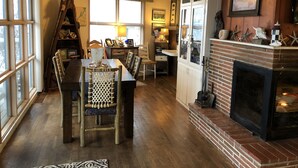 Un comedor acogedor con una mesa y sillas de madera, una chimenea y un ventilador de techo.