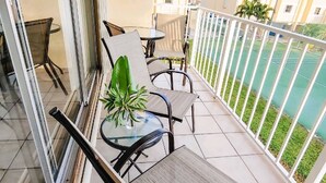A balcony with two chairs and a table, a potted plant, and a view of a sports court. - Work remote, or not at all, in paradise at this cozy, beachy condo!  (Tavernier)