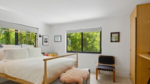 A bedroom with a bed, a bench, a chair, a wardrobe, and two windows with a view of greenery. - Coconut Grove Dream, located in the heart of the village. Beloved by the sailors (Miami)