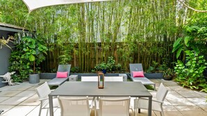 A patio with a table and chairs, surrounded by lush greenery and a bamboo backdrop. - Coconut Grove Dream, located in the heart of the village. Beloved by the sailors (Miami)