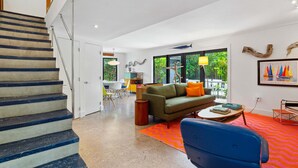 A modern living room with a staircase, a green sofa, a blue chair, and a colorful rug. - Coconut Grove Dream, located in the heart of the village. Beloved by the sailors (Miami)