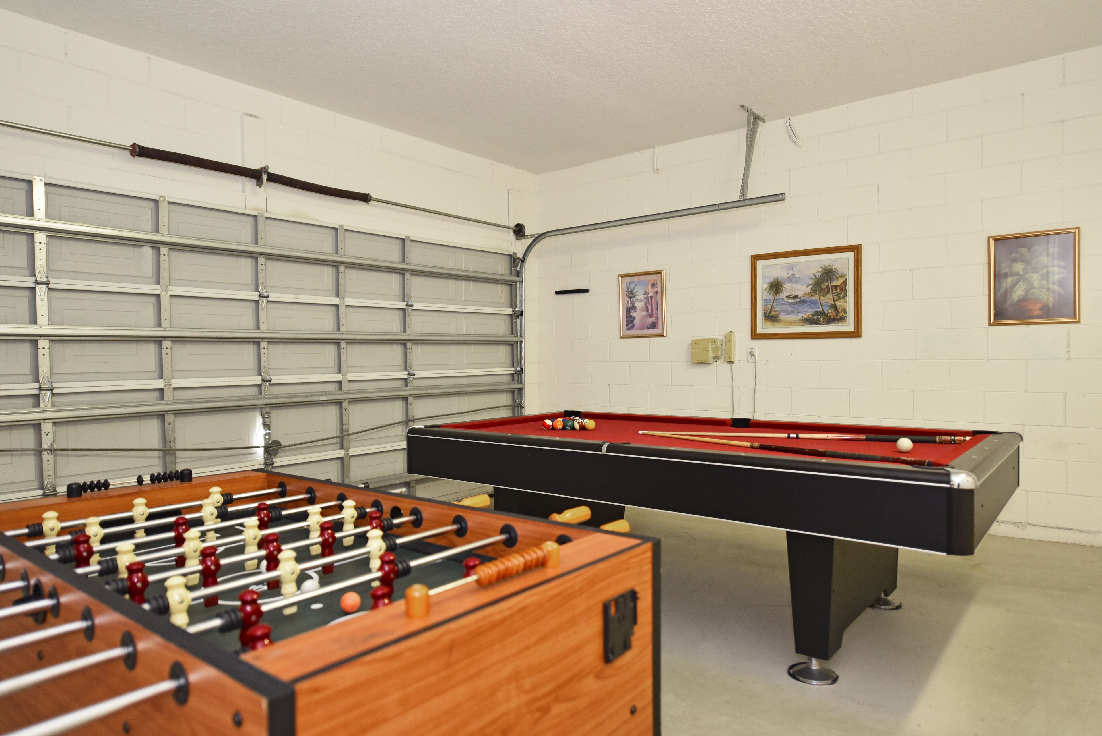 A room with a foosball table and a pool table.