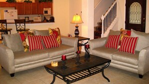 A living room with two grey sofas, a coffee table, and a lamp. There is a staircase leading to a landing with a door. - Spacious, Private Pool/Spa, Nice View, Game Rm, Next to Clubhouse, Gated Resort (Clermont)