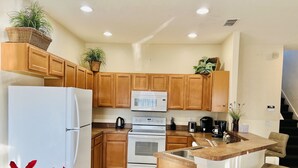 A modern kitchen with wooden cabinets, a white refrigerator, a built-in oven, a microwave, and a coffee maker. - Spacious, Private Pool/Spa, Nice View, Game Rm, Next to Clubhouse, Gated Resort (Clermont)