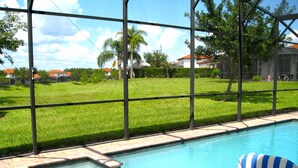 A swimming pool with a view of a green lawn and houses in the background. - Spacious, Private Pool/Spa, Nice View, Game Rm, Next to Clubhouse, Gated Resort (Clermont)