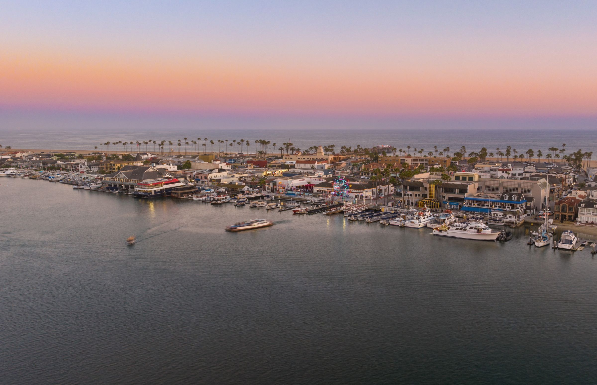 A coastal town with a marina, buildings, and palm trees.