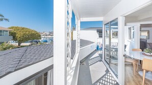 Een balkon met uitzicht op de jachthaven, een eethoek met tafel en stoelen, en een klein zithoekje met een plant.