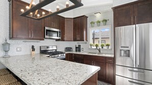 A modern kitchen with dark wood cabinets, stainless steel appliances, and a granite countertop.