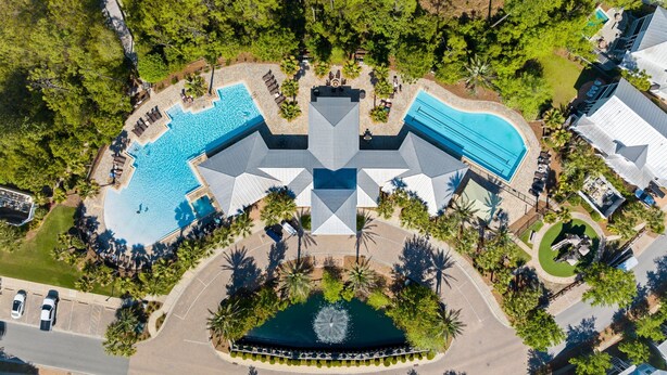 Vista aérea de un complejo turístico con múltiples piscinas, una fuente central y abundante vegetación.