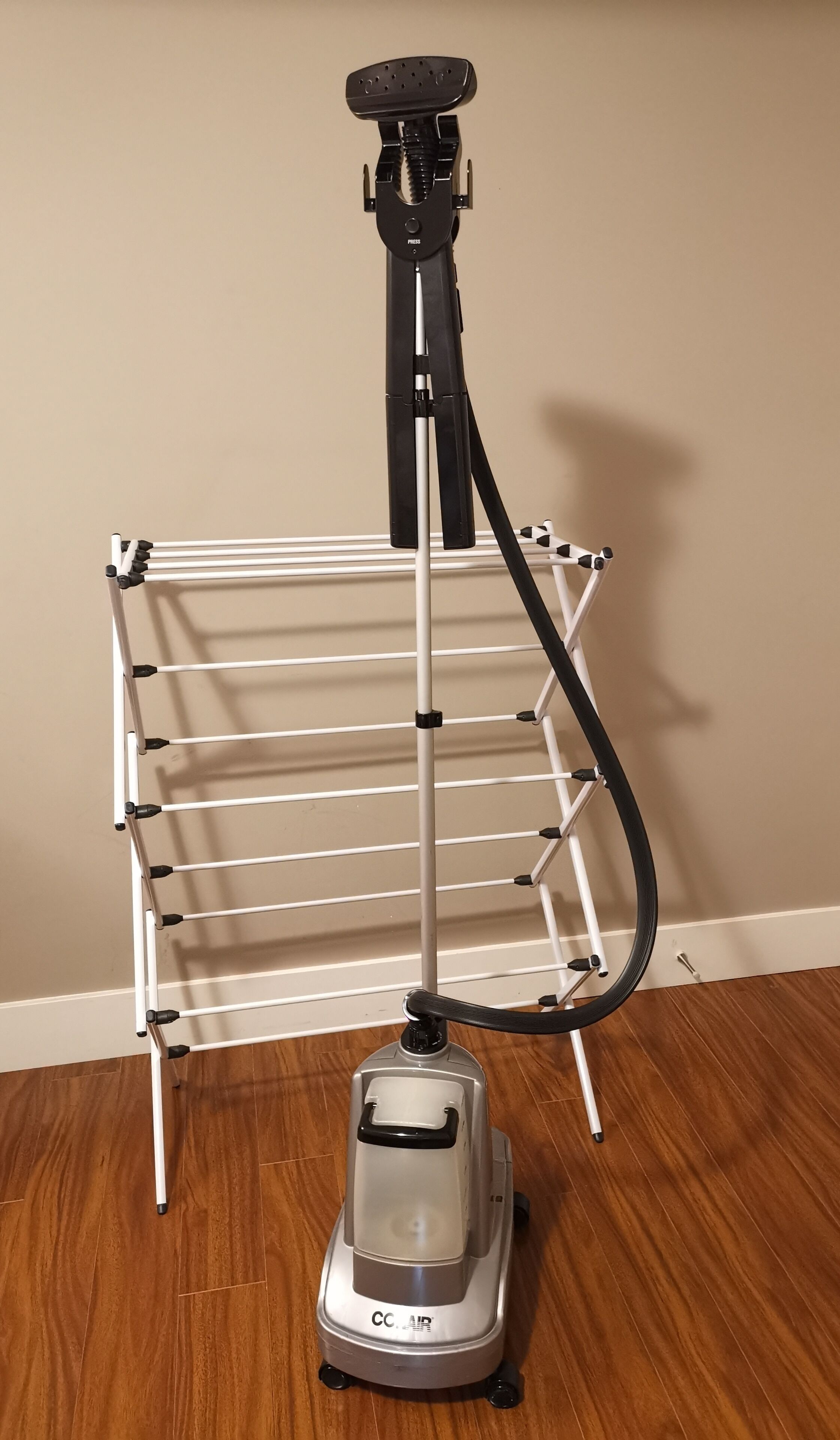 Un aspirateur muni d’un tuyau et d’un étendoir à linge en métal.