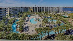 A resort with multiple swimming pools, palm trees, and a large building with balconies.