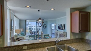 A modern kitchen with granite countertops, stainless steel sinks, and a chandelier.