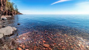 Ein freier Blick auf eine felsige Küstenlinie mit ruhigem Meer und blauem Himmel.