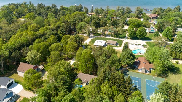 Ett flygbildsbild av ett bostadsområde med hus, en swimmingpool och en strand i bakgrunden.