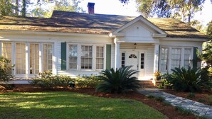 A white house with green shutters, a front porch, and a well-maintained lawn.