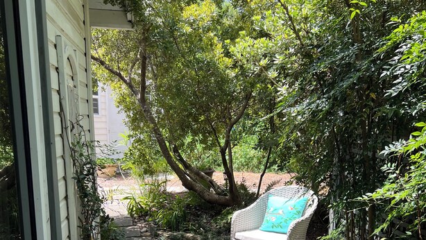 A wooden deck with wicker chairs and a small fountain.