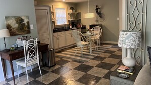 A dining area with a checkered floor, white chairs, a table, and a decorative lamp.