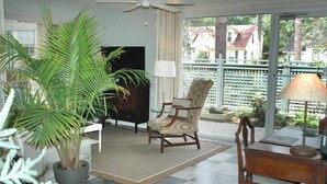 A living room with a TV, a wooden chair, a table, and a potted plant.