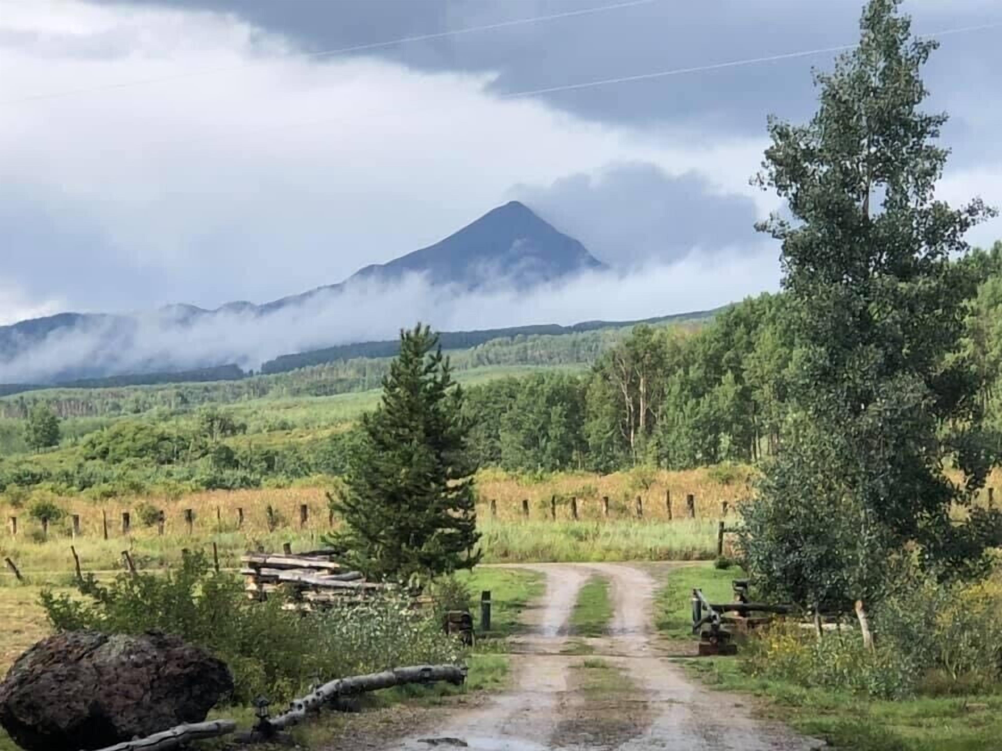 Paisaje rural con un sendero de tierra que lleva a una montaña al fondo.