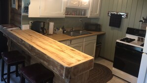 Una cocina con mostradores de madera, estufa, microondas y lavabo.