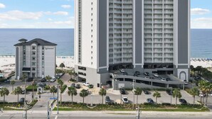 Een meerlaags hotel met een centrale binnenplaats, een parkeergarage en uitzicht op het strand.