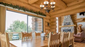 Un interior de madera con una mesa de comedor, sillas, una chimenea de piedra y una estatua de un oso.