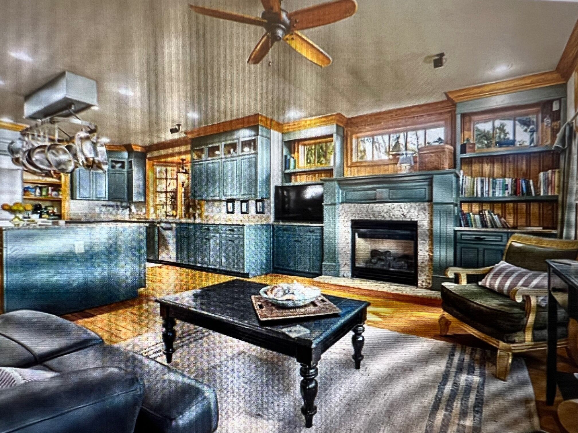A spacious living room with a fireplace, a large bookshelf, and a dining area with a wooden table and chairs.