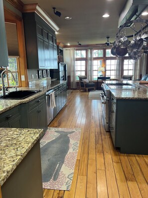 A spacious kitchen with granite countertops, dark cabinetry, and a large island with a built-in oven. - Tranquil Coastal Waterfront- Saltwater Pool/125' Private Dock/Outstanding Sunset (Kitty Hawk)