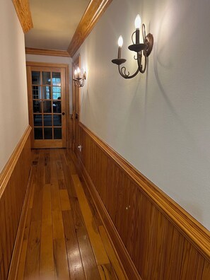 A wooden-paneled hallway with a door at the end.