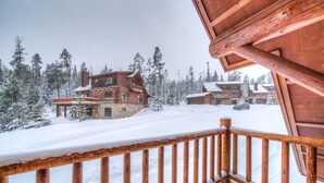 A wooden cabin with a balcony, surrounded by snow-covered trees.