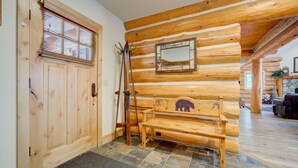 A wooden interior with a bench, a door, and a mirror on the wall.