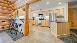 A modern kitchen with wooden cabinets, a stainless steel refrigerator, and a built-in microwave.