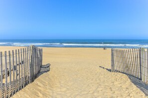 A sandy beach with a wooden fence leading to the ocean. - Beautiful Condo, Close to the Beach and Plenty of Room for Your Family! (Ocean City)