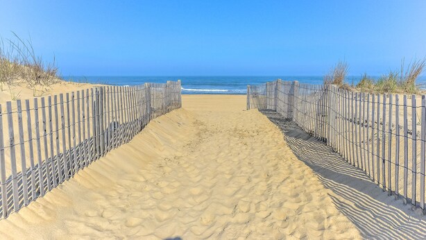 A sandy beach path leading to the ocean, flanked by wooden fences. - Beautiful Condo, Close to the Beach and Plenty of Room for Your Family! (Ocean City)