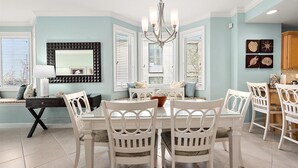A dining area with a white table and chairs, a chandelier, and a large mirror on the wall. - Beautiful Condo, Close to the Beach and Plenty of Room for Your Family! (Ocean City)