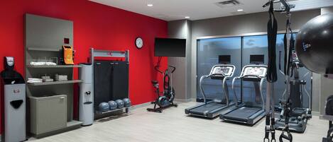 Un gimnasio con cintas de correr, una bicicleta estática y una máquina de pesas.
