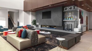 A modern living room with a fireplace, sofas, and a flat-screen TV. - Hilton Garden Inn Denver/Thornton (Thornton)