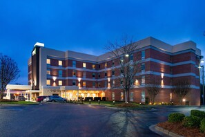 A multi-story hotel with a brick facade, a covered entrance, and a parking area.