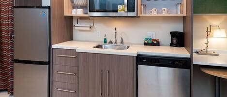 A compact kitchen with a stainless steel refrigerator, a microwave, and a dishwasher.