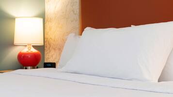 A hotel room with a bed, a red lamp, and a clock displaying 4:05.