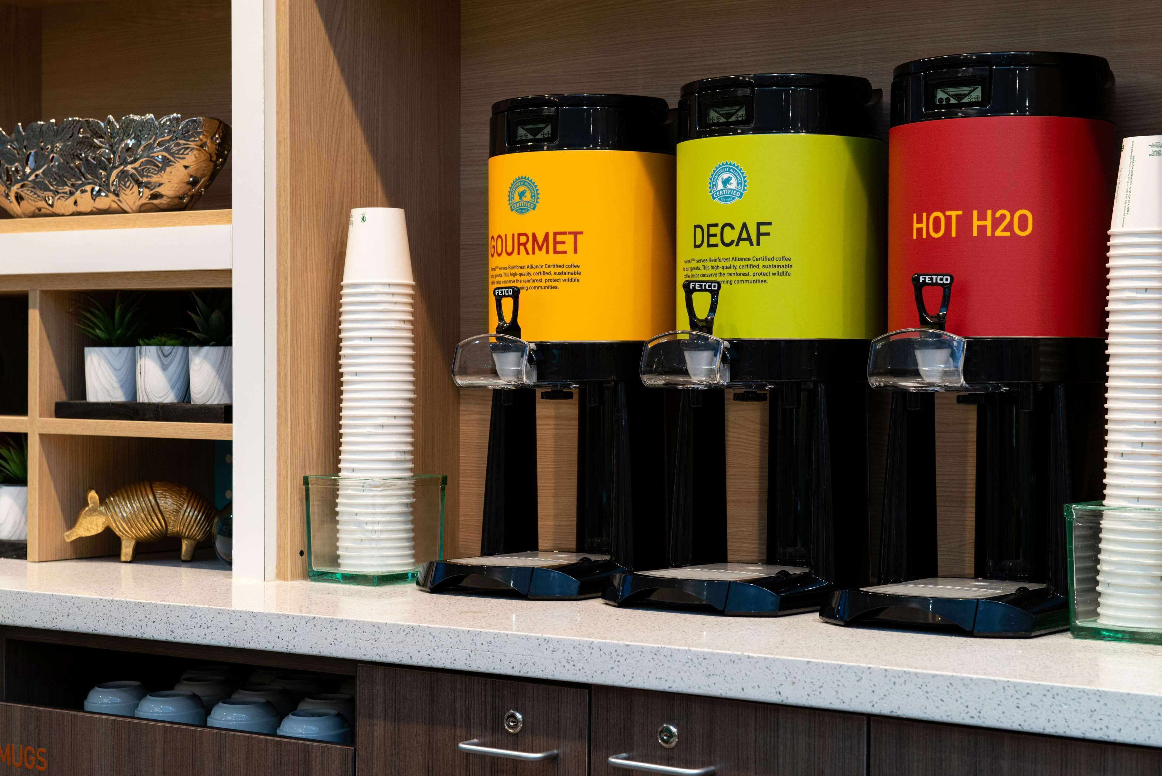 A coffee station with three dispensers labeled 'GOURMET', 'DECAF', and 'HOT H2O'.