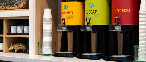 A coffee station with three dispensers labeled 'GOURMET', 'DECAF', and 'HOT H2O'.