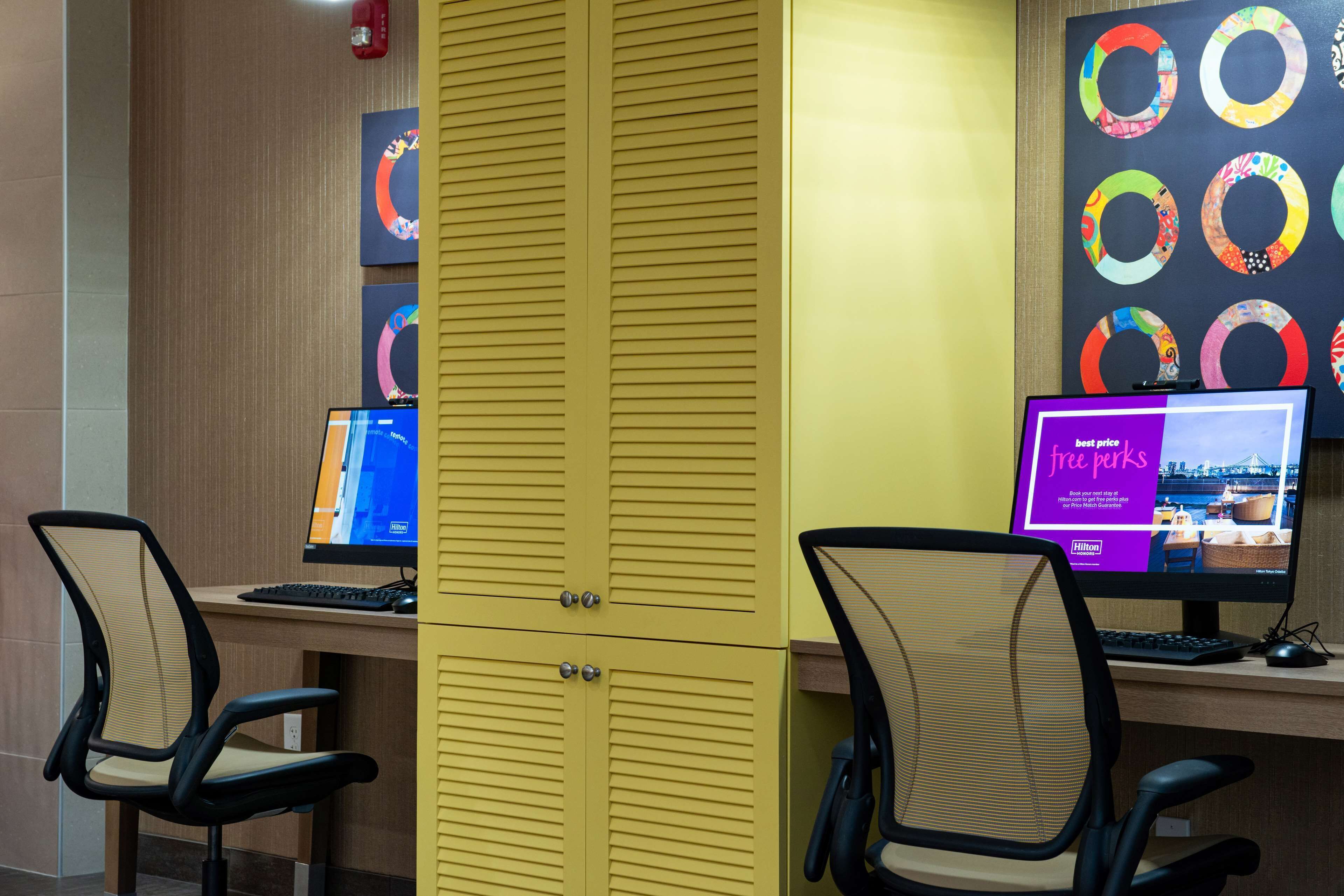 A workspace with two desks, each with a computer monitor, keyboard, and chair.