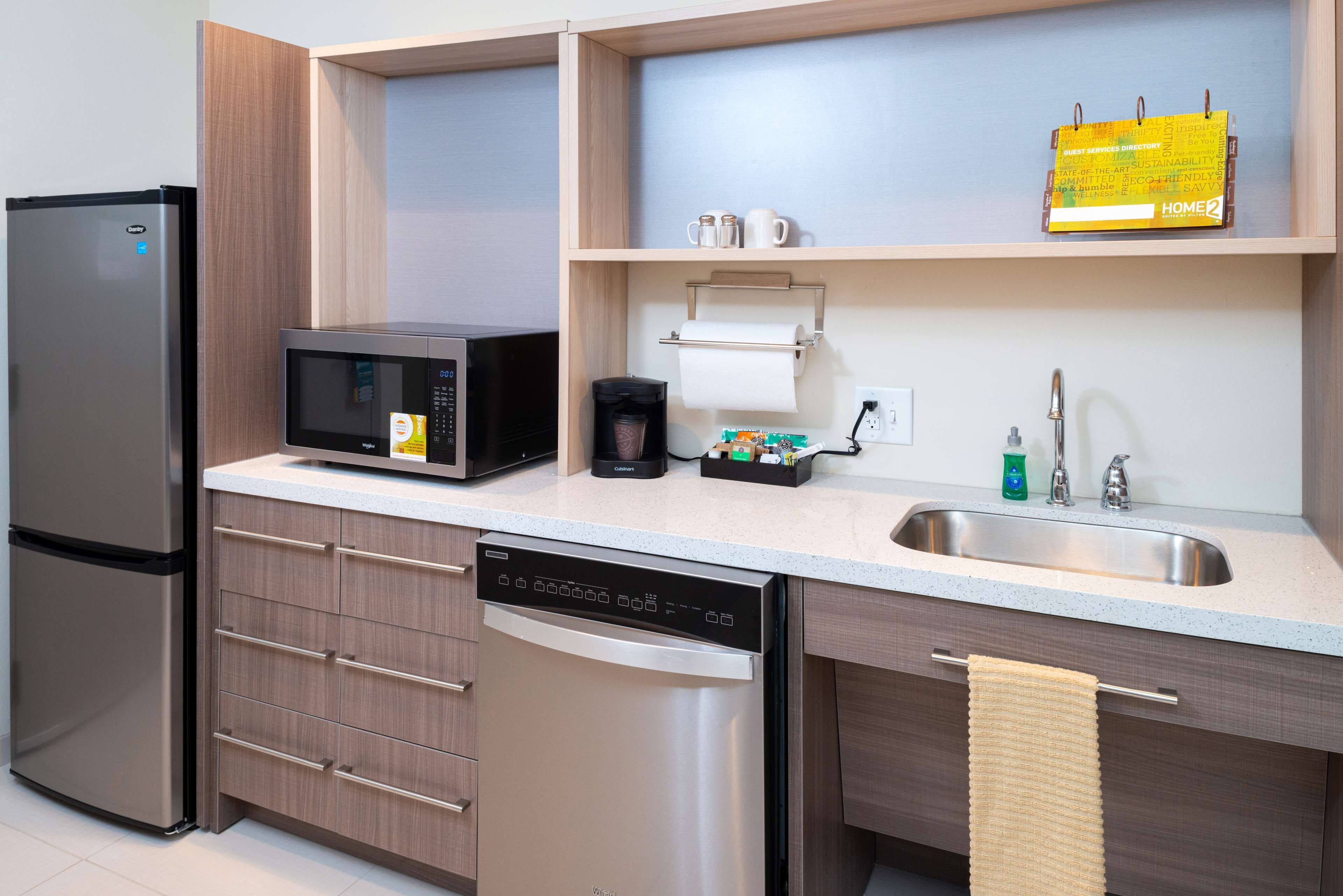 A modern kitchen with a stainless steel refrigerator, microwave, dishwasher, and a sink with a towel rack.