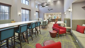 A modern dining area with high tables, chairs, and a mix of red and green seating. - Hampton Inn & Suites Grandville Grand Rapids South (Grandville)