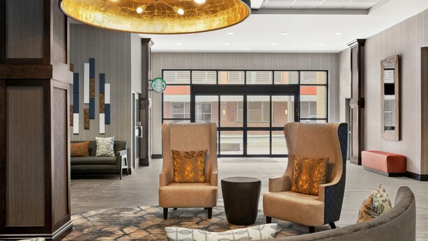Een hal met twee fauteuils, een bijzettafeltje en een grote kroonluchter.